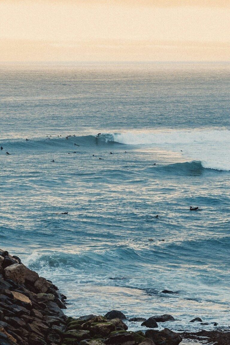 Surfers waiting for waves in the blue ocean under a soft warm sky