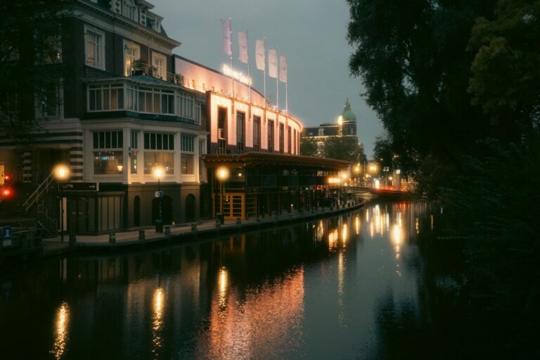 The Holland Casino building illuminated at night along a canal in Amsterdam